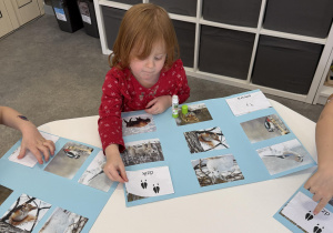 dzieci przy stołach wykonują karty pracy