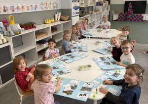 dzieci przy stołach wykonują karty pracy