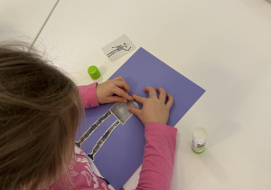 dzieci przy stołach wykonują karty pracy