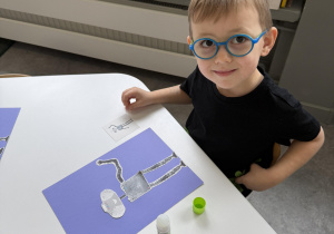 dzieci przy stołach wykonują karty pracy