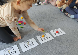 Dziewczynka układająca pociąg z klocków na dywanie