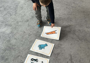 Dziecko układające obrazki związane z pierwszą pomocą na dywanie