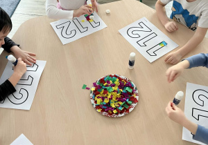 Dzieci podczas wykonywania pracy plastycznej przy stolikach