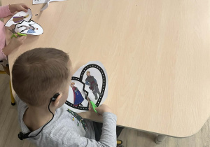 Chłopiec podczas wykonywania pracy plastycznej przy stoliku