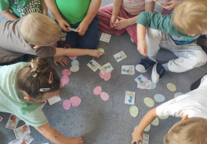 Dzieci podczas układania kart z przeliczaniem na dywanie