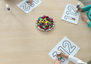 Dzieci podczas wykonywania pracy plastycznej przy stolikach