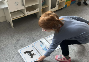 Dziewczynka układająca plansze na dywanie