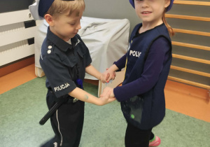 Dzieci w strojach policjantów podczas zabaw tanecznych na sali gimnastycznej