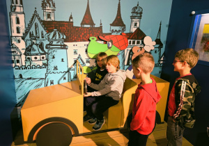 Dzieci siedzą w atrapie samochodu z Filmu Baltazar