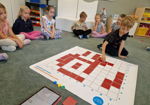 dziecko układa obrazek z kwadratów na podłodze