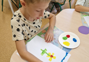 chłopiec maluje obrazek stawiając kropki patyczkiem higienicznym