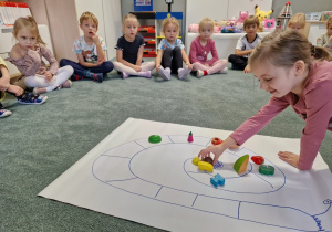 dziewczynka układa kształty owoców na grze planszowej