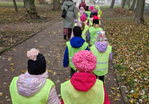 dzieci idą po chodniku w kamizelkach obrzakowych