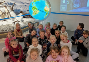 dzieci pozują do zdjęcia na tle globusa