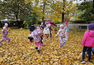 dzieci bawią się pośród liści jesiennych
