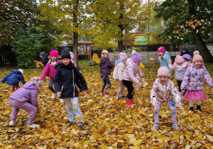 dzieci bawią się pośród liści jesiennych