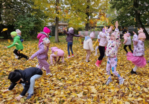 dzieci bawią się pośród liści jesiennych