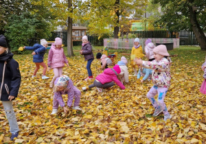 dzieci bawią się pośród liści jesiennych