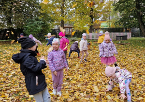dzieci bawią się pośród liści jesiennych