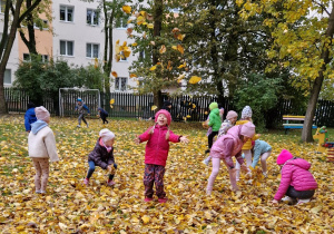 dzieci bawią się pośród liści jesiennych