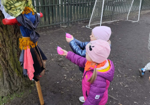 Dzieci w ogrodzie przedszkolnym polewają marzannę wodą