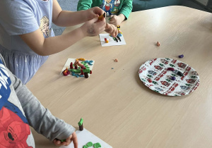 Dzieci przy stoliku lepiące ludziki z plasteliny