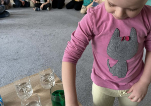 Dziewczynka wkładająca bibułę do szklanki z wodą