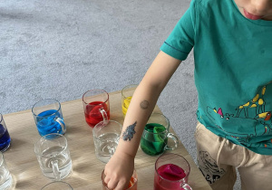 Dziecko wkładające bibułę do szklanki z wodą