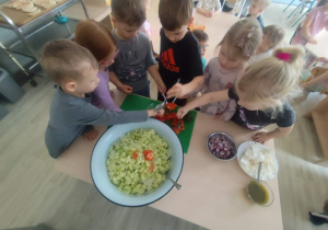 Dzieci dodające składniki do sałatki greckiej