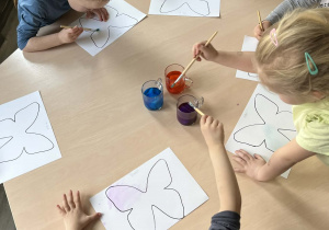 Dzieci malujące przy stolikach farbami wykonanymi z bibuły