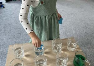 Dziewczynka umieszczająca bibułę w szklance z wodą