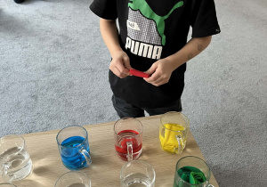 Chłopiec umieszczający bibułę w szklance z wodą