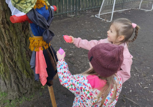Dzieci polewające marzannę w ogrodzie przedszkolnym