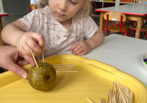 Dziewczynka podczas tworzenia jeżyka z owoców