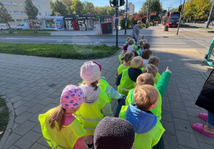 Dzieci podczas spaceru na skrzyżowanie czekają na zielone światło, by móc przejść przez jezdnię