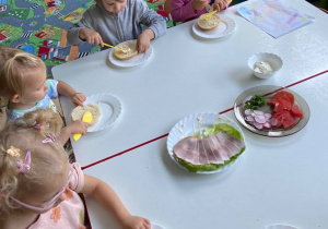 Dzieci przy stolikach samodzielnie przygotowują kanapki