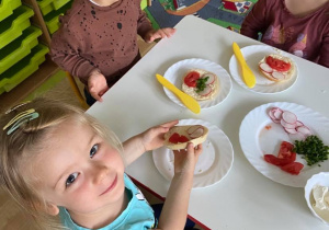 Dzieci przy stolikach samodzielnie przygotowują kanapki