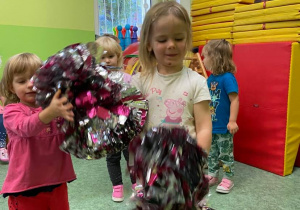 Dzieci tańczą z pomponami do muzyki na sali gimnastycznej