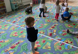 Dzieci na dywanie udają żabki