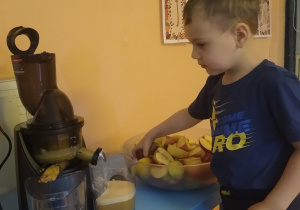 chłopiec wrzuca jabłko do sokowirówki
