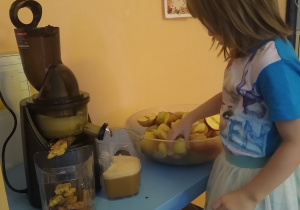 dziewczynka wrzuca jabłko do sokowirówki