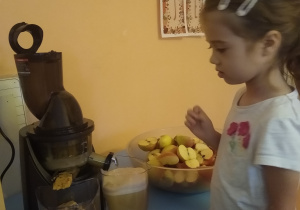 dziewczynka wrzuca jabłko do sokowirówki