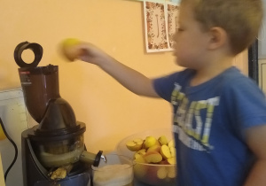 chłopiec wrzuca jabłko do sokowirówki