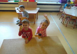 dzieci siedzą przy stoliku i pokazują zrobione przez siebie grzybki