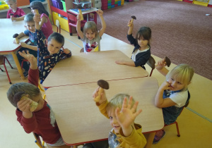 dzieci siedzą przy stoliku i pokazują zrobione przez siebie grzybki