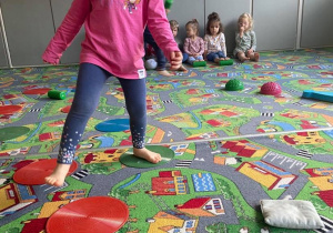 Dziewczynka pokonuje tor przeszkód na dywanie