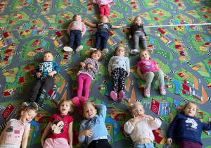 Dzieci na dywanie leżą na kształt wieży Eiffla