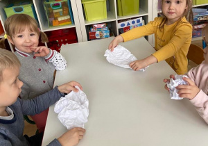 Dzieci przy stoliku lepią śnieżkę z papieru