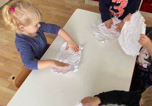Dzieci przy stoliku lepią śnieżki z papieru