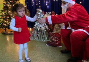 Dziewczynka odbiera prezent od Świętego Mikołaja